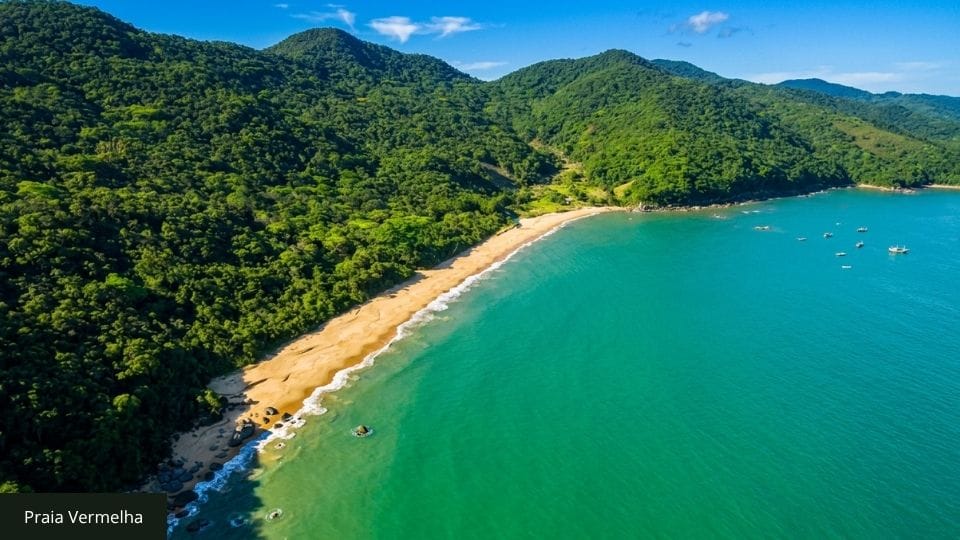 Praia com areia avermelhada, costão rochoso, última parada da trilha Costeira dos Zimbros em Bombinhas.