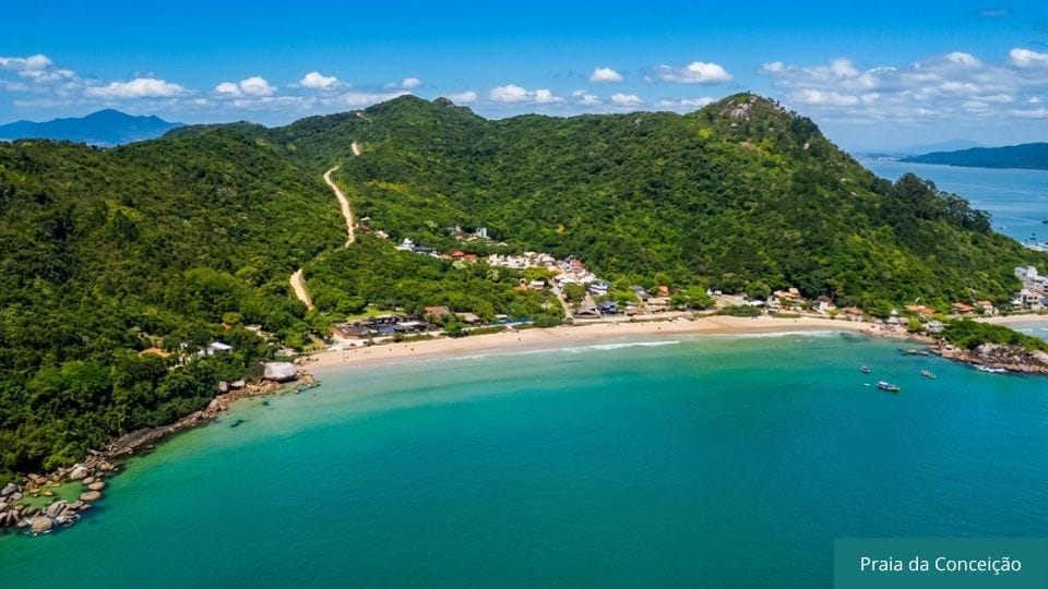 Praia da Conceição com água cristalina e bandeira azul em dia de mar calmo.
