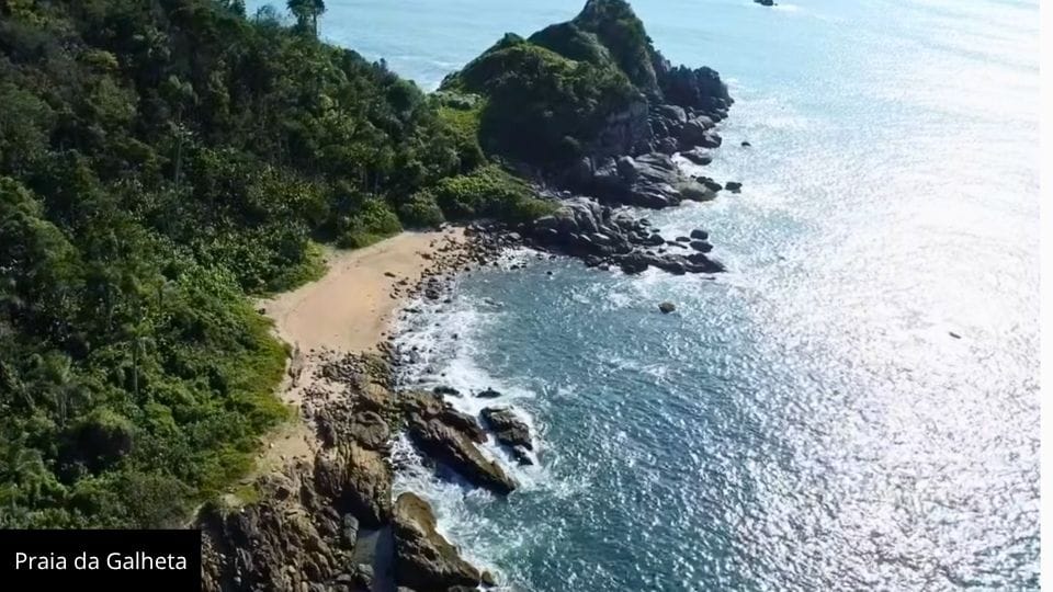 Praia da Galheta em Bombinhas com águas cristalinas e faixa de areia pequena entre rochas.