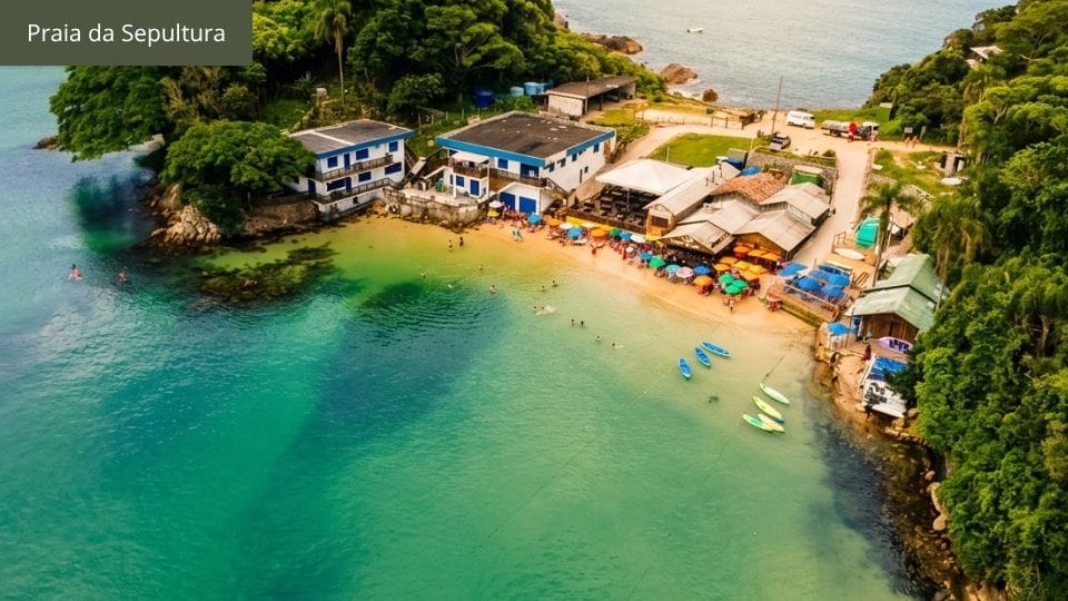Praia da Sepultura com restaurante à beira-mar e costão rochoso em Bombinhas.