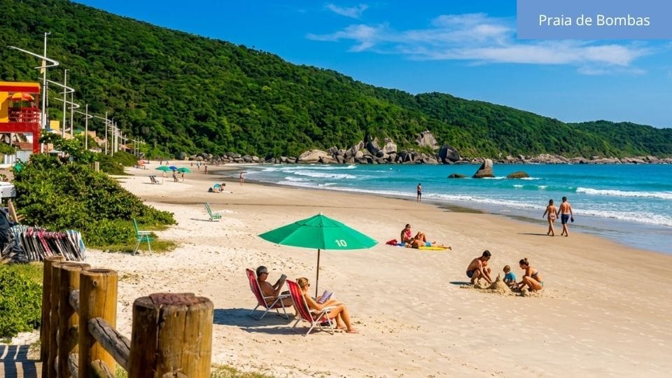 Praia de Bombas com ampla faixa de areia, estrutura de praia e muitos visitantes durante o dia.