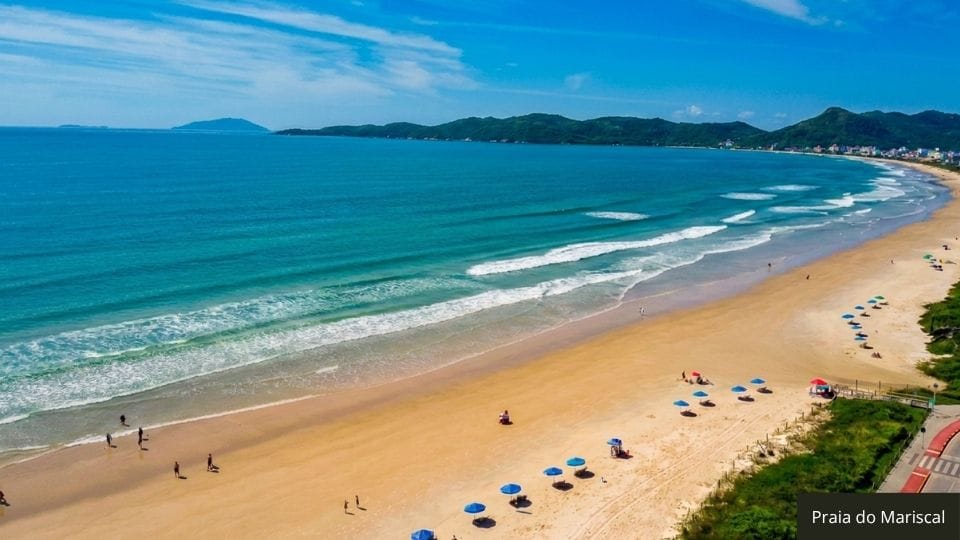Praia do Mariscal com faixa de areia ampla, estrutura e visitantes em dia calmo.