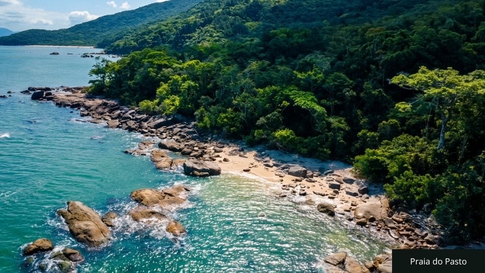 Praia com acesso difícil via trilha, costão rochoso e mar selvagem, com piscinas naturais visíveis na Costeira dos Zimbros.