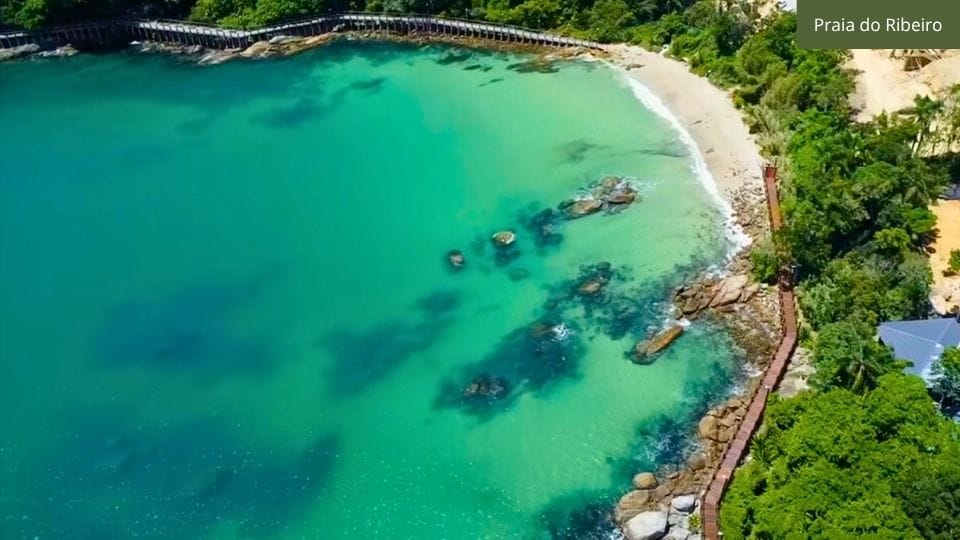 Passarela de deck branco conectando praias em Bombinhas, com vista do mar cristalino.