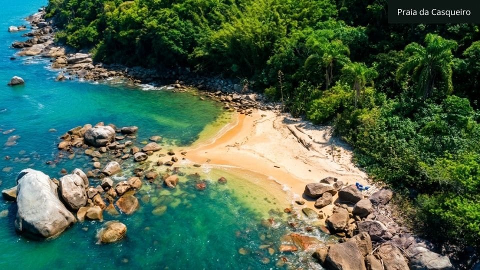 Praia arenosa com formações rochosas e piscinas naturais, parada tranquila na sequência da trilha Costeira dos Zimbros.