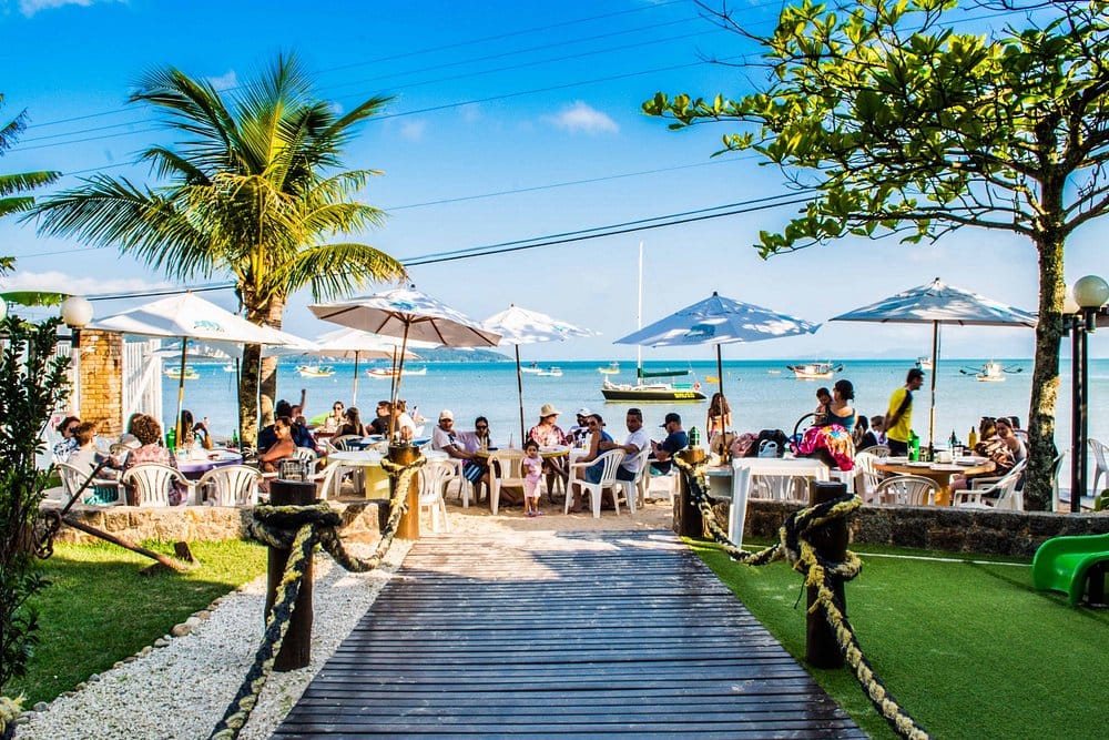 Restaurante Berro D'Água em Zimbros — mesas na areia com vista para a baía, Bombinhas/SC